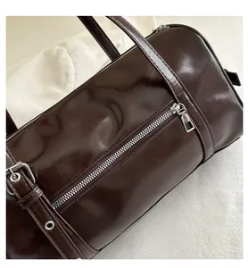 Detail of dark brown glossy leather Boston bag with silver zipper and stitching