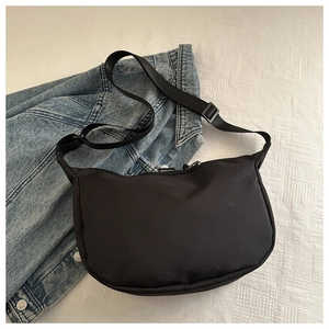 Vue de dessus d'un sac demi-lune en nylon noir sur un fond de tissu texturé blanc