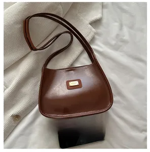 Detail of a brown vintage oil-waxed PU leather shoulder bag with a gold metal logo
