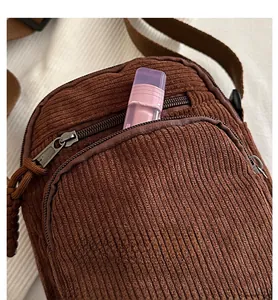 Gros plan du sac bandoulière en velours côtelé marron montrant le rangement pour rouge à lèvres