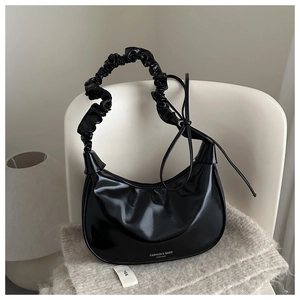 Detailed view of the black glossy pleated hobo bag with ribbon and mirror-like texture