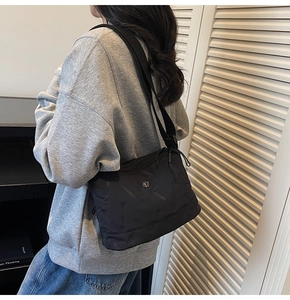 Détail du sac à bandoulière en tissu oxford noir avec broderie losange et logo en métal