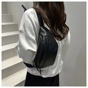 Close-up of minimalist black PU leather crossbody bag with lychee grain texture and zipper
