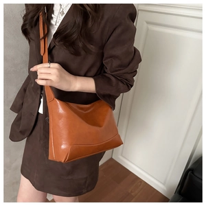 Close-up of caramel leather tote bag showing reinforced edges and shoulder strap details