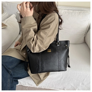 Detail showing high-quality black faux leather texture with elegant gold hardware logo