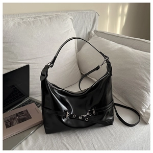 Dettaglio di borsa hobo in pelle lucida nera con fibbia argentata su divano bianco