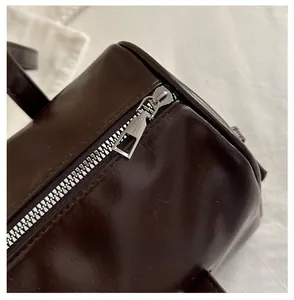 Detailed macro view of the silver metal zipper and dark brown leather texture of the bag
