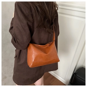 Brown leather tote bag showing shoulder carry fit and large capacity on a model