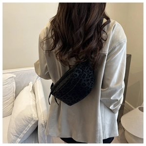 Detail of black leopard print crossbody bag worn over a beige suit with adjustable strap