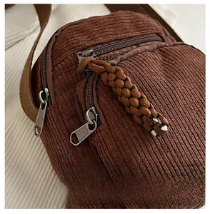 Détail de la bandoulière en velours côtelé marron avec fermetures en métal doré
