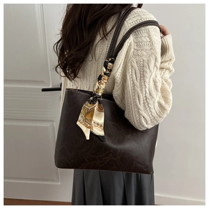 Détail d'un sac cabas marron foncé vintage avec foulard décoratif en soie sur la bandoulière