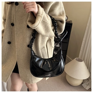 Detail of black pleated cloud bag with shiny PU leather texture and ruffle strap