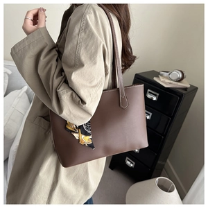 Detail of brown leather tote bag with decorative printed silk scarf and fine stitching