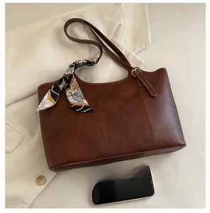 Detail of vintage brown tote bag with silk scarf and phone for size reference