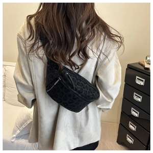 Rear view of model wearing a black leopard print crossbody bag in a stylish home setting