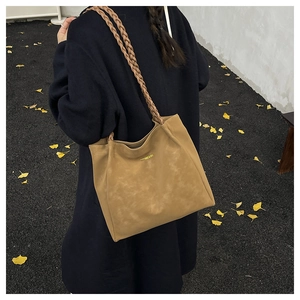 Detail of khaki suede tote bag with braided rope straps and gold lettering logo