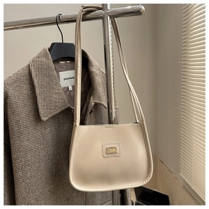 Close-up of beige PU leather shoulder bag featuring a metallic logo and sleek minimal design