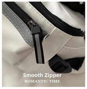 Detail shot of smooth black nylon zipper and gray reflective trim on white saddle bag