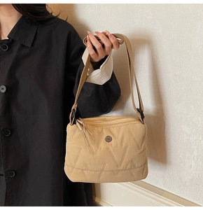 Détail du sac bandoulière beige en tissu oxford avec surpiqûres en V et logo rond