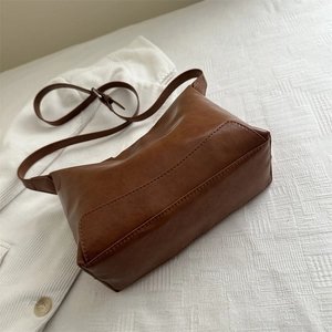 Minimalist brown soft leather tote bag with adjustable shoulder strap on white fabric