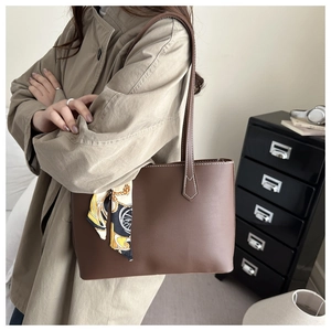 Close-up of vintage brown tote bag with contrast stitching and decorative silk scarf detail