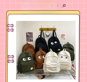 Detail view of corduroy backpacks with cartoon eyes and star pendants in various colors