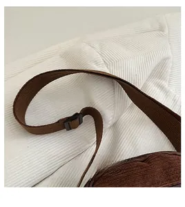 Détail de la bandoulière réglable en nylon et de la boucle noire du sac en velours