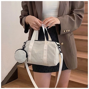 Détail du sac polochon en nylon crème avec petit porte-monnaie rond sur des escaliers