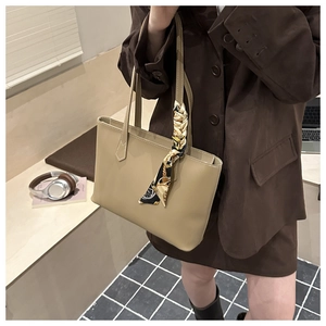 Detail of khaki faux leather tote bag with elegant silk scarf wrapped around handle