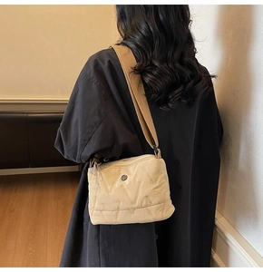 Détail de la bandoulière large et du logo métallique sur sac beige matelassé chic