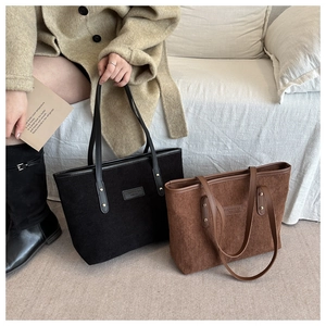 Close-up of corduroy tote bags with leather straps and minimalist brand label detailing