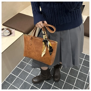 Sac cabas en cuir marron avec détail de foulard en soie porté par un mannequin