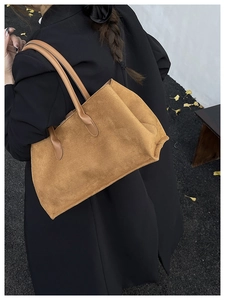Brown faux suede tote bag shown on model shoulder against an autumn street background