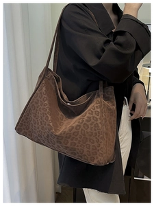 Side view of large leopard print suede tote bag worn over the shoulder on a black coat