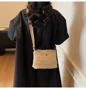 Détail du sac bandoulière Oxford beige matelassé avec motif en V et fermeture à pompon
