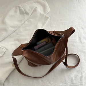 Brown leather tote bag showing large capacity with phone, wallet and lipstick inside