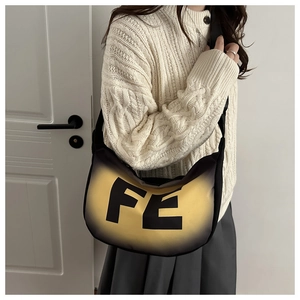 Détail du sac à bandoulière dégradé noir et jaune avec lettrage FE et sangle large