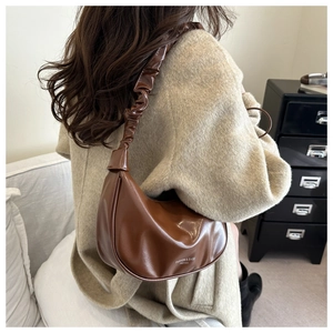 Close-up of brown PU crescent bag featuring a stylish pleated strap and minimalist design