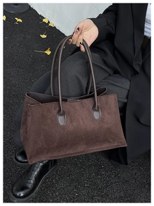 Close-up of a dark brown matte suede tote bag with side pleats and slim leather handles