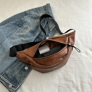 Retro brown PU leather chest bag with large capacity on denim jacket background
