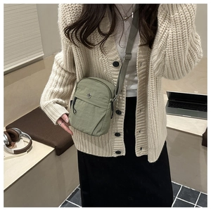 Detailed view of an olive green crossbody bag made of waterproof nylon with logo detail
