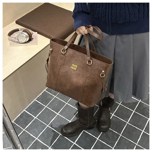 Detail of vintage brown leather tote bag featuring yellow logo for casual commute style