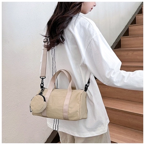 Détail du sac cylindrique beige montrant la texture en nylon et la mini pochette amovible