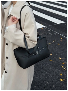 Detail of black matte tote bag featuring silver buckles and grommets on shoulder straps