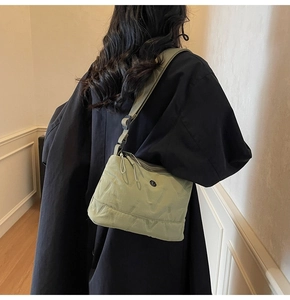 Détail du sac bandoulière matelassé en nylon vert clair porté par le mannequin
