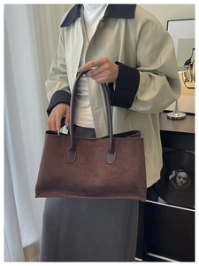 Deep brown suede tote bag held by model in a minimalist and elegant interior setting