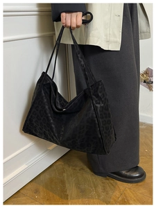 Detail of vintage black suede tote bag with leopard pattern and dual shoulder straps