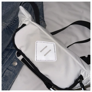 Detailed close-up of white sporty waist bag with black strap on denim jacket backdrop