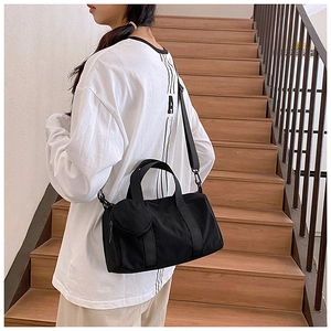 Détail d'un sac à bandoulière en nylon noir avec mini porte-monnaie amovible sur la sangle