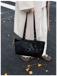 Detail of vintage black leather tote bag with silver eyelets and buckle strap details